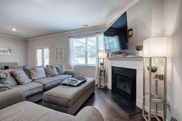 living room featuring wood finished floors, ornamental molding, a glass covered fireplace, and visible vents