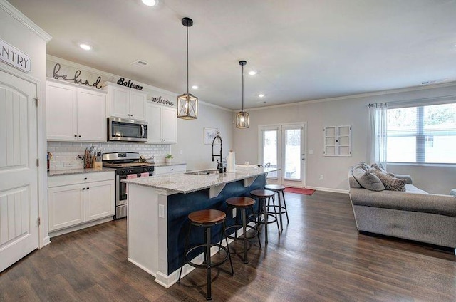 kitchen with decorative backsplash, a kitchen breakfast bar, stainless steel appliances, crown molding, and a sink