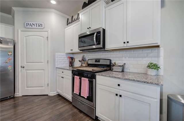 kitchen featuring white cabinets, ornamental molding, stainless steel appliances, and dark wood finished floors