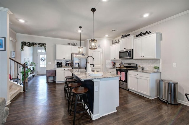 kitchen featuring dark wood finished floors, stainless steel appliances, a kitchen bar, white cabinetry, and a sink