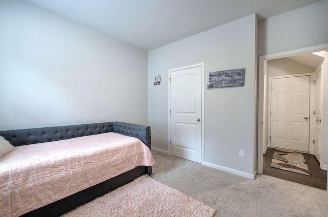 carpeted bedroom featuring lofted ceiling and baseboards