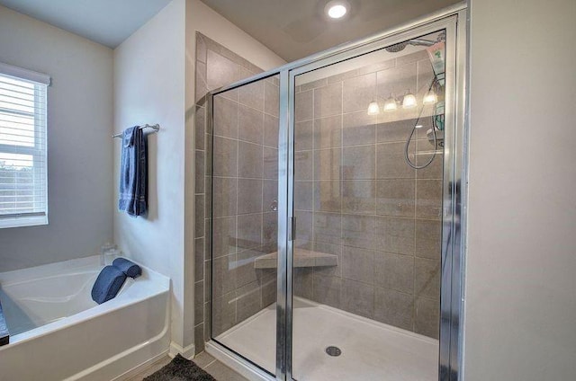 bathroom featuring a stall shower and a bath