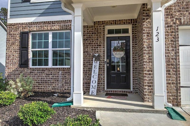 doorway to property with covered porch and brick siding