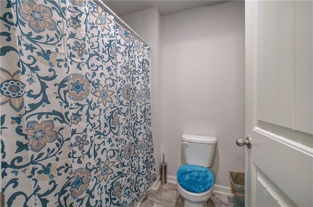 full bathroom featuring baseboards and toilet