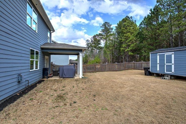 view of yard with a shed, fence, and an outbuilding