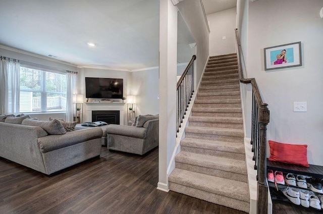 living room featuring dark wood-style floors, a fireplace, crown molding, stairway, and baseboards