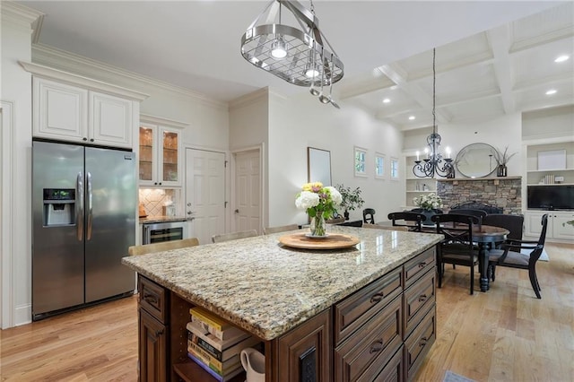 kitchen featuring stainless steel fridge with ice dispenser, a chandelier, light wood-style flooring, white cabinets, and light stone countertops
