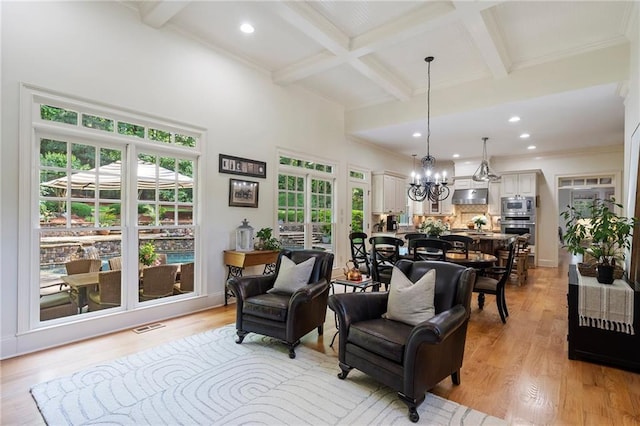 living area with beamed ceiling, coffered ceiling, a chandelier, ornamental molding, and light wood-type flooring