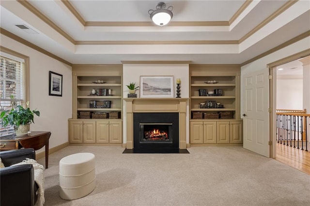 living area featuring a raised ceiling, crown molding, carpet flooring, a fireplace with flush hearth, and built in features