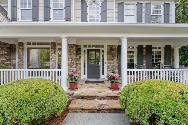 doorway to property featuring a porch and stone siding
