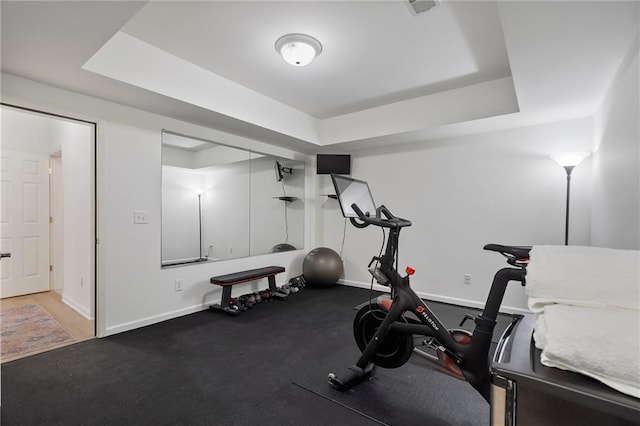 exercise room with a tray ceiling and baseboards