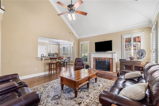 living room with a brick fireplace, ornamental molding, wood finished floors, and ceiling fan