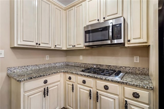 kitchen with cream cabinetry and appliances with stainless steel finishes