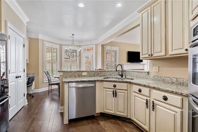kitchen with a sink, cream cabinets, appliances with stainless steel finishes, and a chandelier
