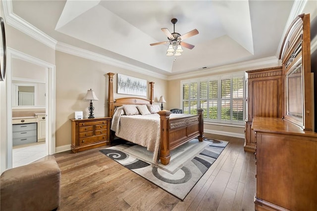 bedroom featuring wood-type flooring, a raised ceiling, ornamental molding, and baseboards