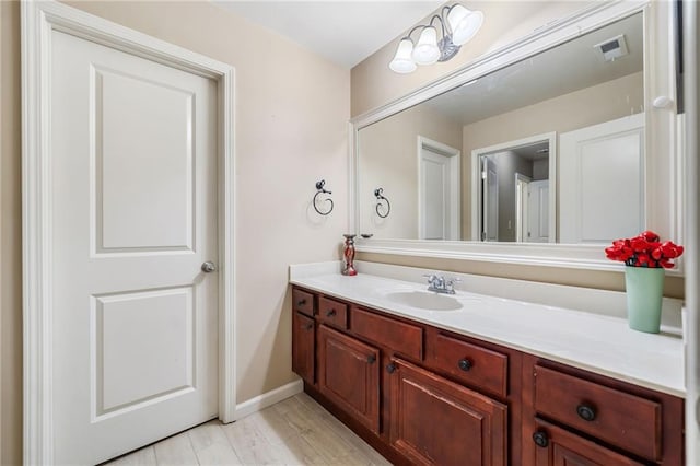 bathroom with baseboards, visible vents, wood finished floors, and vanity