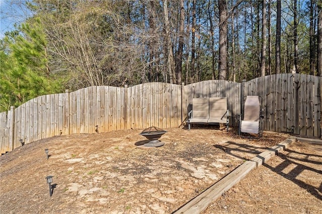 view of yard featuring a fenced backyard and a fire pit