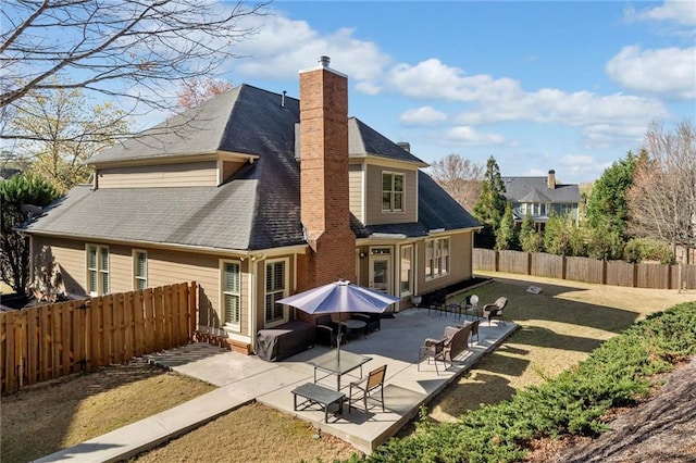 back of property with a fenced backyard, a patio, a lawn, and a chimney