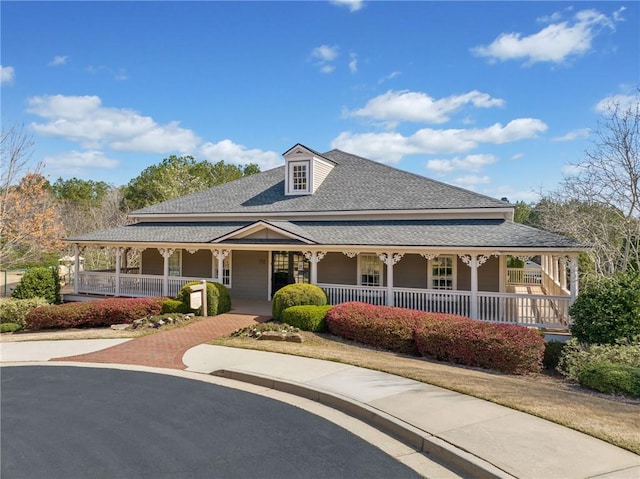 farmhouse-style home featuring covered porch and a shingled roof