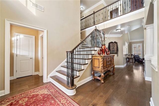 staircase featuring decorative columns, visible vents, crown molding, and hardwood / wood-style flooring