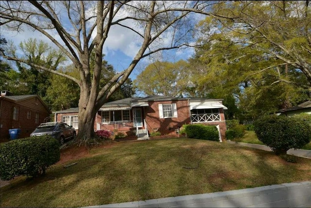 view of front of property with brick siding, a front lawn, and covered porch