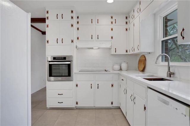 kitchen with white dishwasher, black electric stovetop, under cabinet range hood, stainless steel oven, and a sink