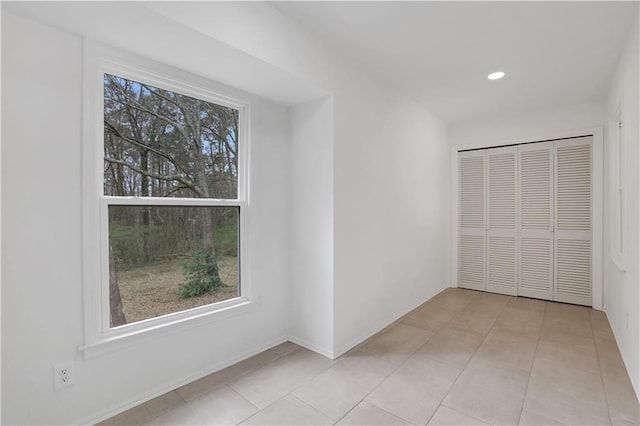 unfurnished bedroom with recessed lighting, a closet, light tile patterned flooring, and baseboards