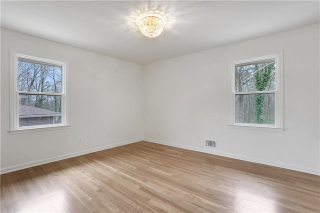 empty room featuring baseboards, light wood finished floors, and a healthy amount of sunlight