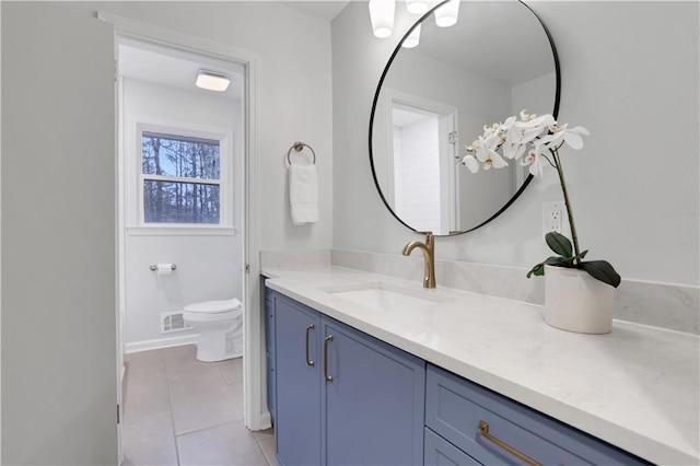 bathroom featuring toilet, vanity, baseboards, visible vents, and tile patterned floors