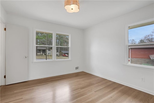 unfurnished room featuring baseboards, wood finished floors, and a healthy amount of sunlight