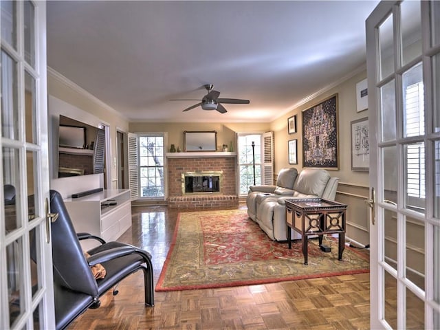 living room with parquet flooring, ornamental molding, ceiling fan, a brick fireplace, and french doors