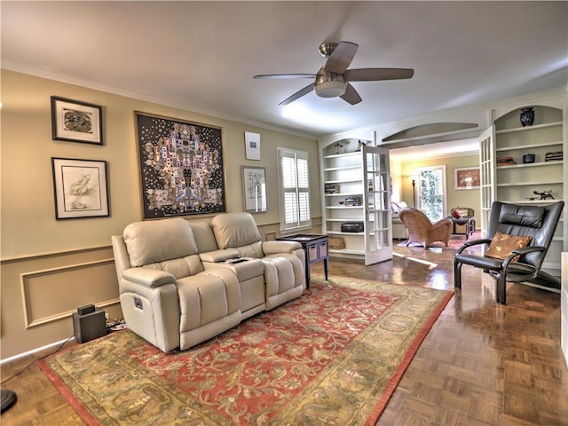 living room featuring ceiling fan, ornamental molding, dark parquet flooring, and built in shelves