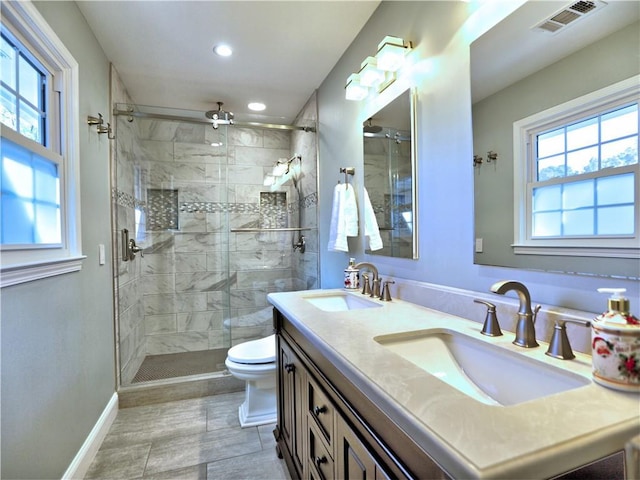 bathroom featuring vanity, toilet, a shower with shower door, and a wealth of natural light