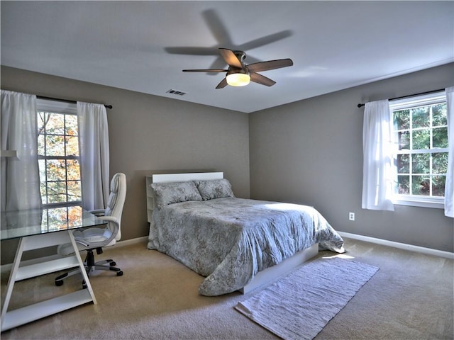 carpeted bedroom with multiple windows and ceiling fan