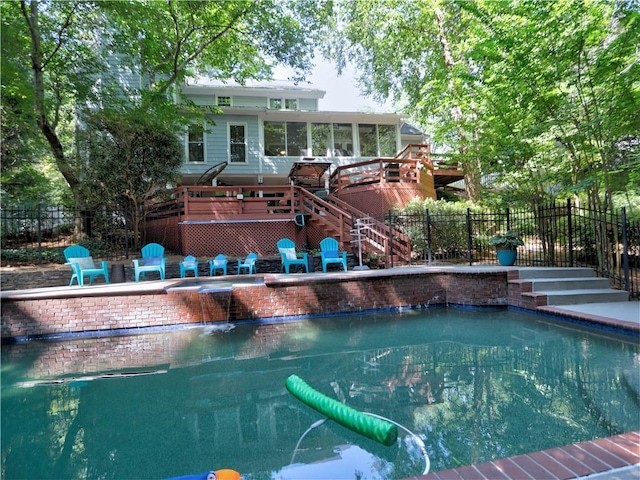 view of swimming pool featuring a wooden deck and a sunroom