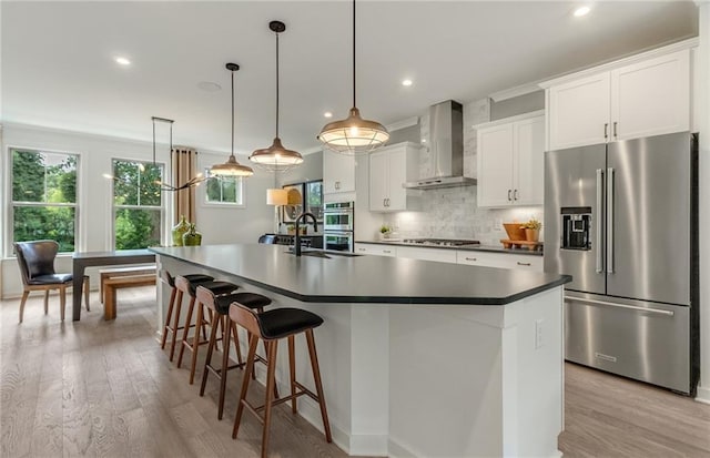 1088 Battery Park Rd, Decatur, GA 30033 - kitchen featuring appliances with stainless steel finishes, wall chimney range hood, a sink, light wood-style floors, and recessed lighting