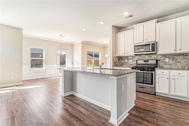 kitchen featuring stone countertops, appliances with stainless steel finishes, dark wood-style flooring, ornamental molding, and an island with sink