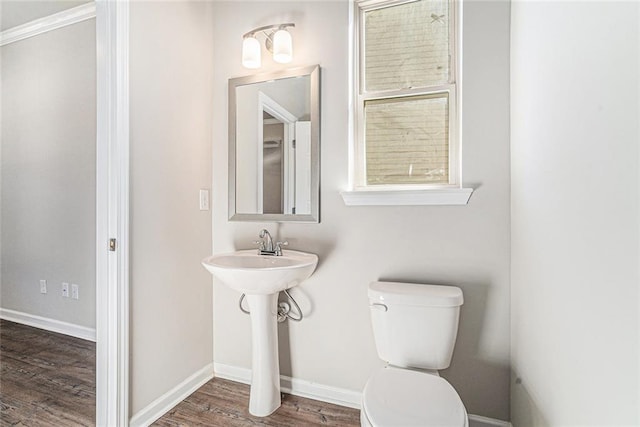 bathroom with toilet, baseboards, and wood finished floors