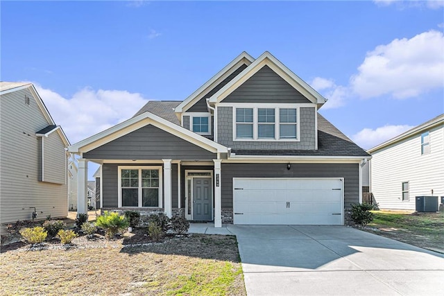 craftsman-style home featuring stone siding, a garage, concrete driveway, central air condition unit, and a porch