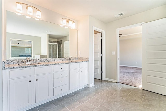 full bath with a stall shower, baseboards, visible vents, a sink, and double vanity