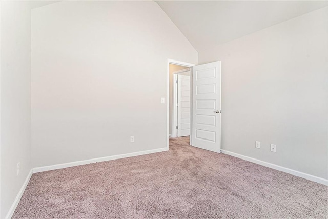 carpeted spare room with vaulted ceiling and baseboards