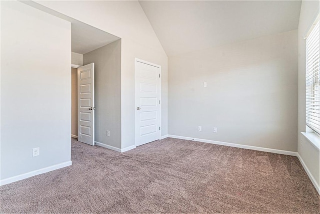 spare room with lofted ceiling, carpet floors, and baseboards