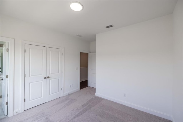 unfurnished bedroom with light colored carpet and a closet