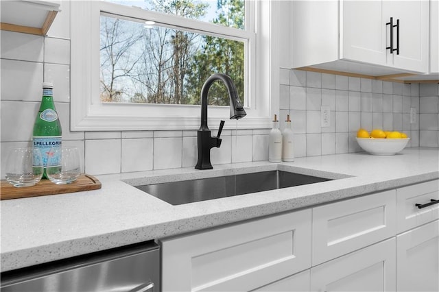 room details featuring sink, white cabinetry, light stone countertops, and tasteful backsplash