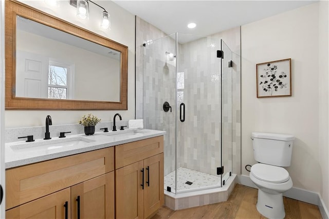 bathroom with hardwood / wood-style flooring, toilet, vanity, and a shower with door