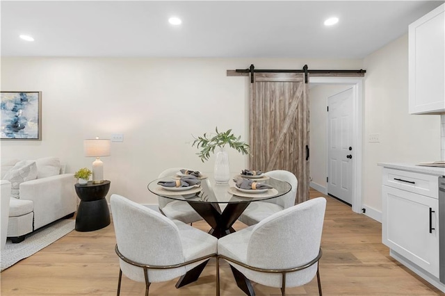 dining space with light hardwood / wood-style floors and a barn door