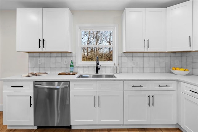 kitchen with decorative backsplash, sink, white cabinetry, and dishwasher