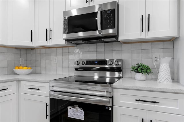 kitchen featuring stainless steel appliances, white cabinetry, light stone counters, and backsplash