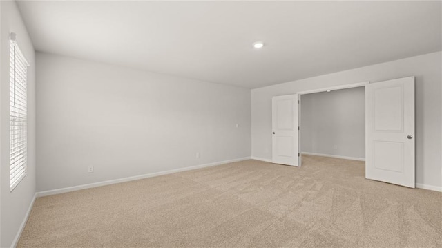 unfurnished bedroom featuring light carpet and a closet