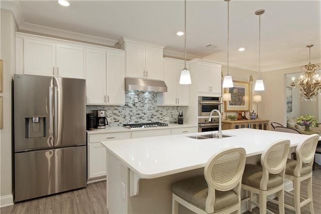 kitchen featuring a center island with sink, stainless steel appliances, ornamental molding, a sink, and under cabinet range hood